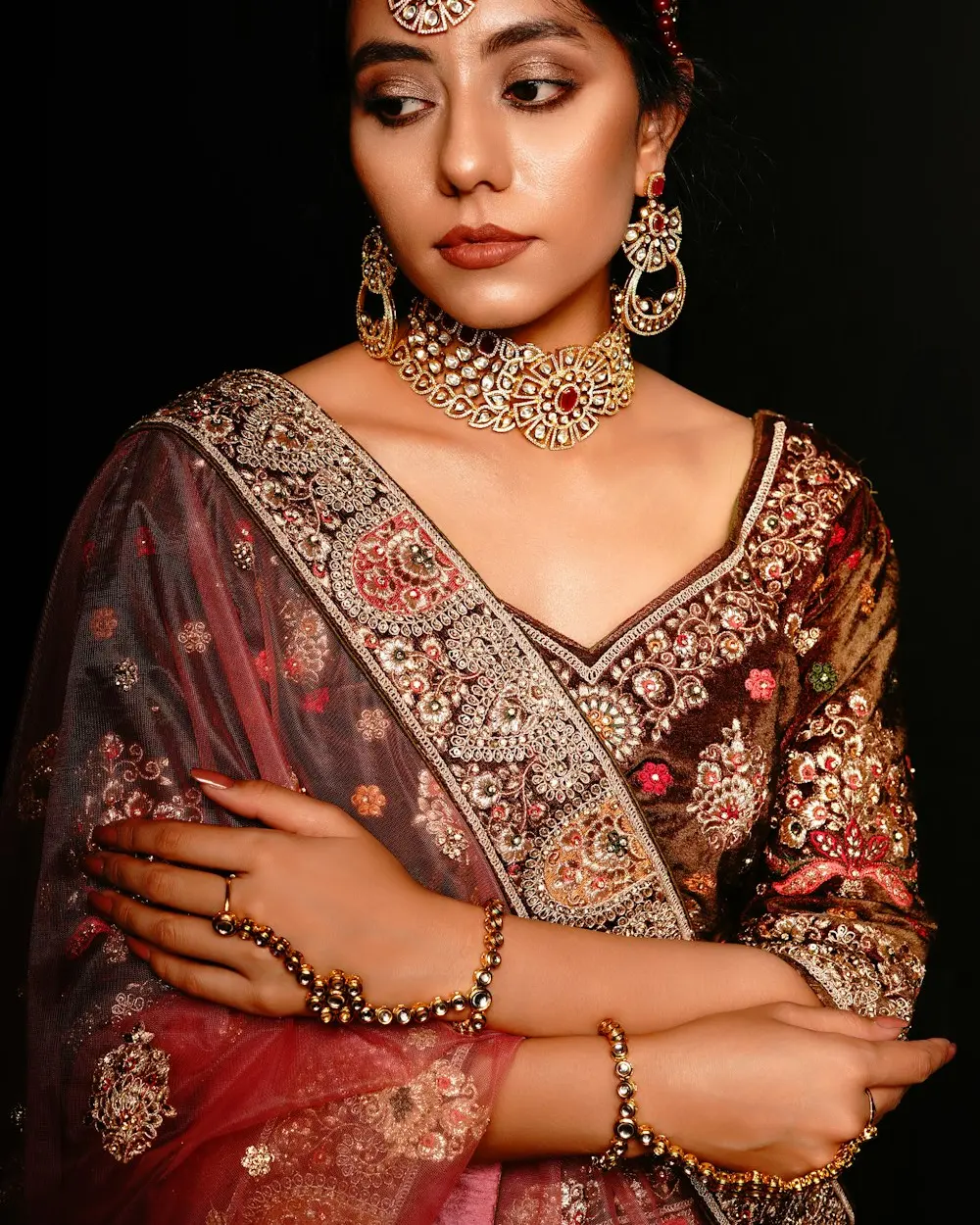 Bride wearing heavy gold jewellery and an embroidered maroon saree