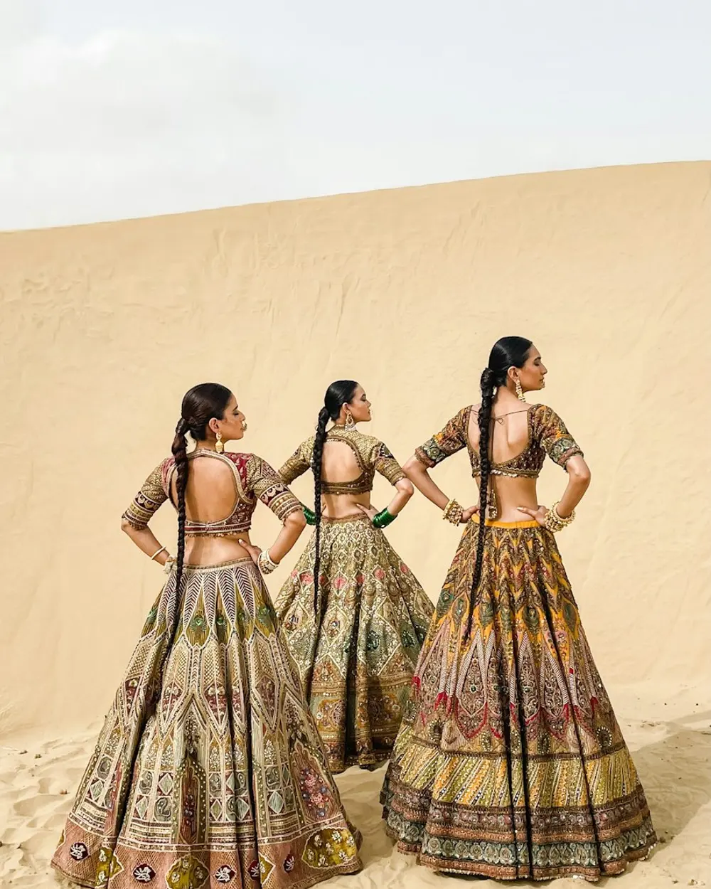 Three women in printed lehengas in a desert